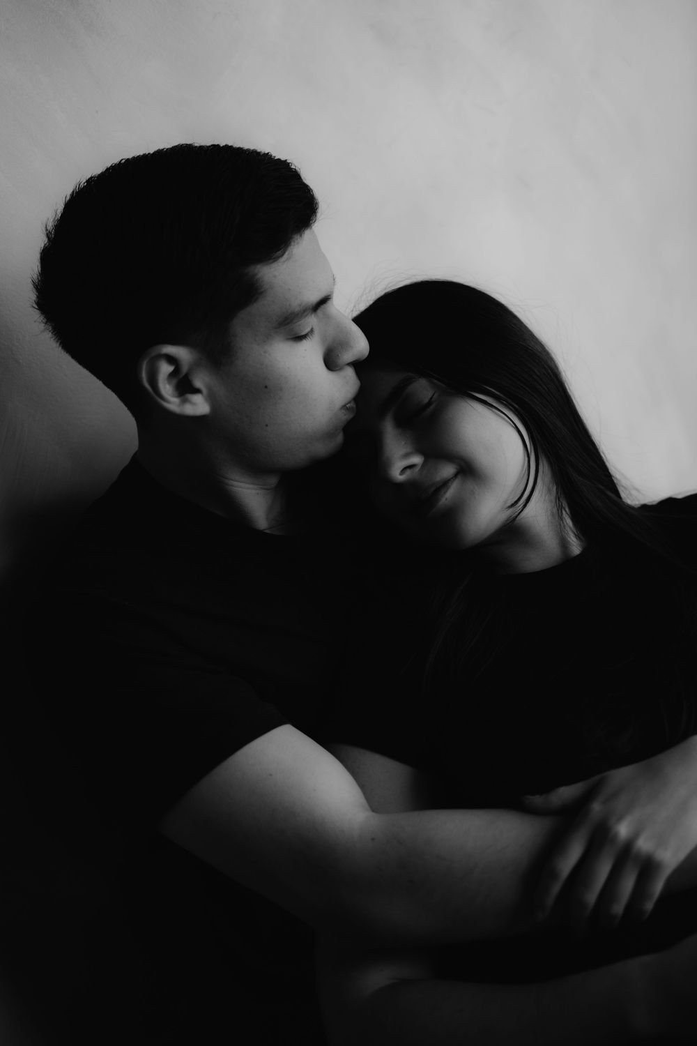 En blanco y negro, una pareja se abraza de cerca, con los ojos cerrados.