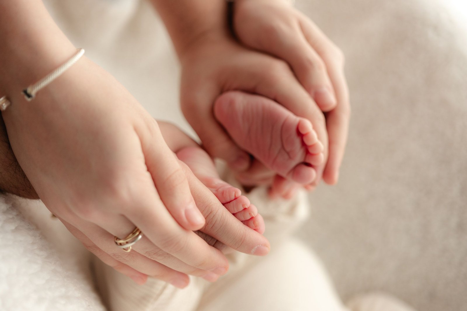 Las manos de mamá y papá sostienen los pies de su bebé recién nacido.