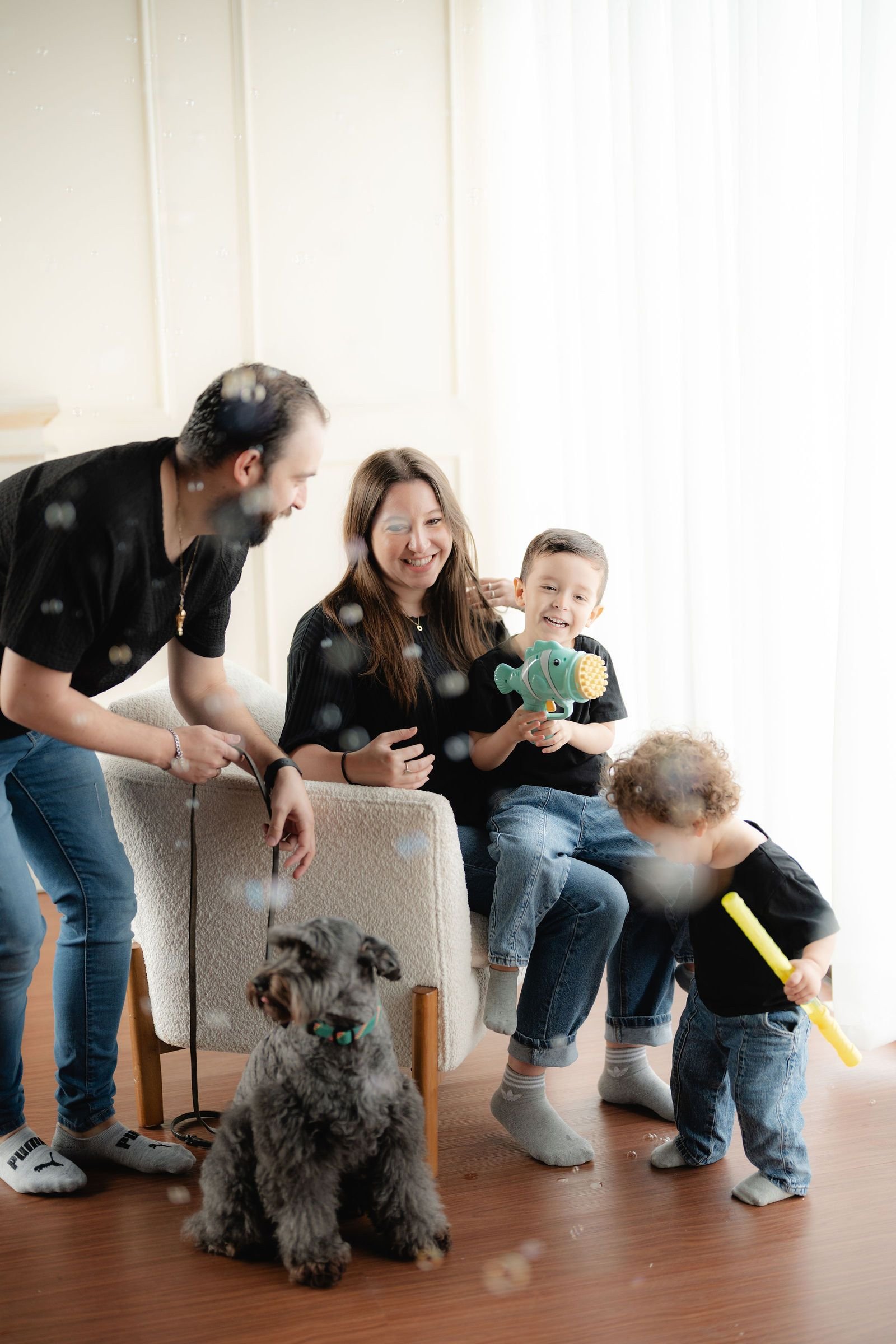 Una familia juega en el piso del estudio con su perro y sus hijos pequeños.