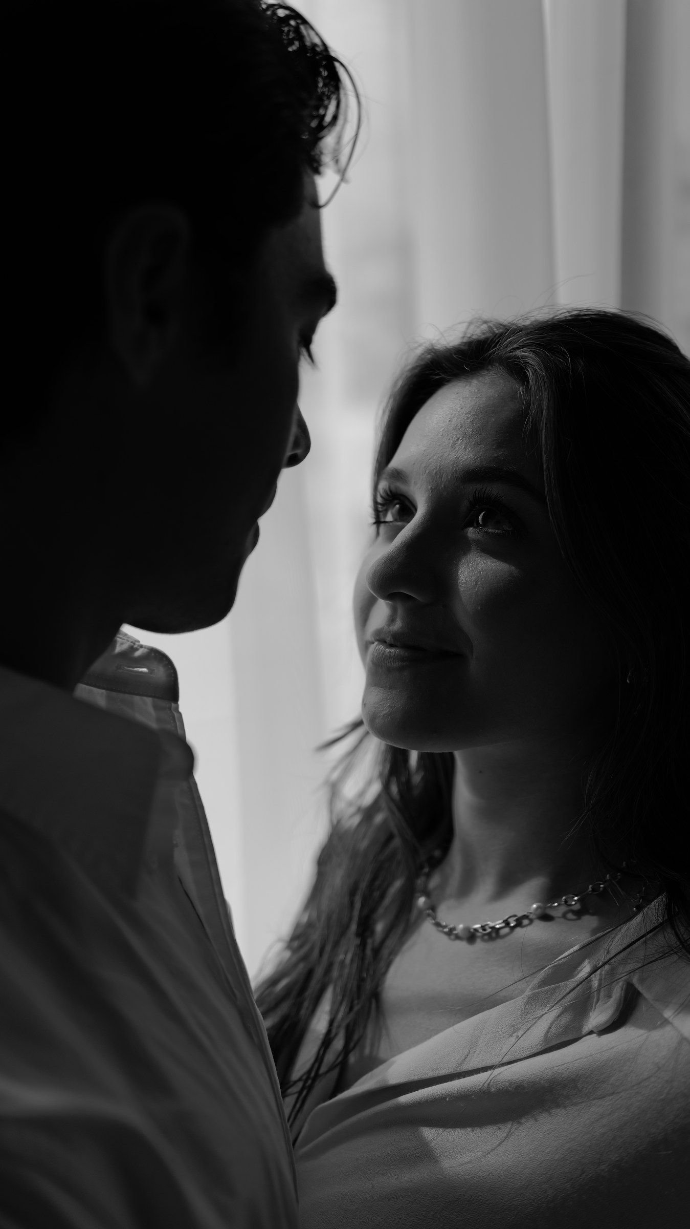 En blanco y negro, ella mira de cerca a su pareja, que apoya la cara en su mano.